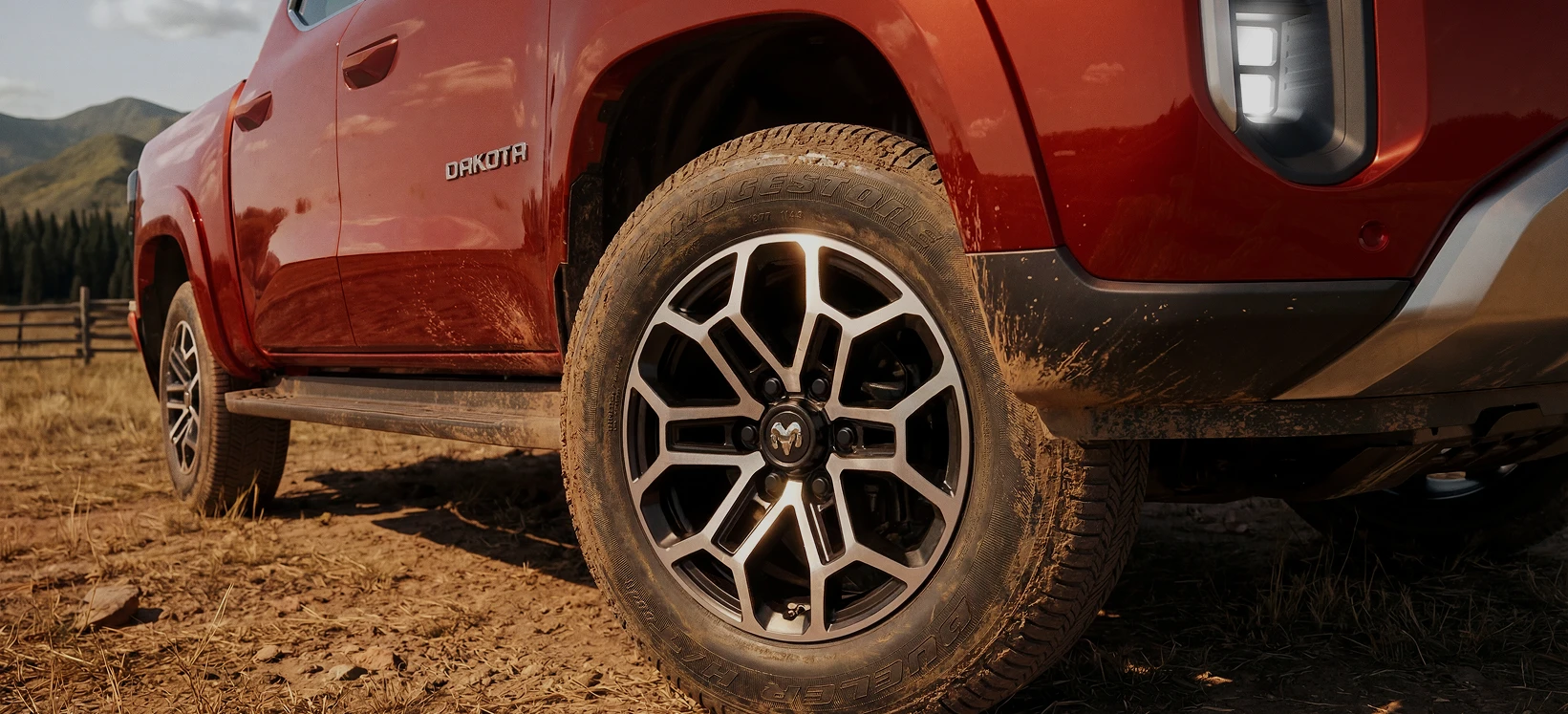 Roda da Ram Dakota no off-road Detalhe da roda da Ram Dakota com pneu off-road sujo de terra sobre terreno de terra seca.